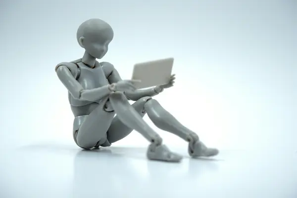 A robot sitting behind a laptop